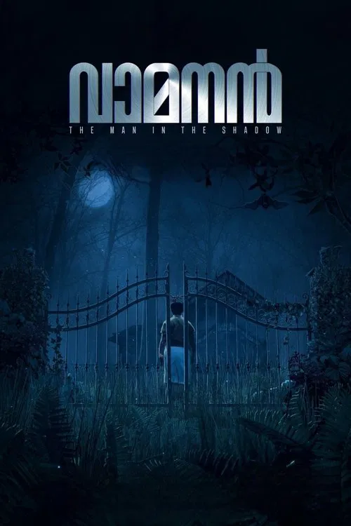A dark, atmospheric movie poster for the Malayalam film “Vamanan – The Man in the Shadow.” A lone man in a white dhoti stands facing a tall, closed iron gate at night, surrounded by dense foliage. Moonlight filters through trees, casting blue-toned shadows and creating a mysterious, suspenseful mood. The film title appears prominently at the top against the night sky.